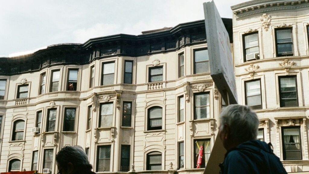 People holding a large sign in front of buildings